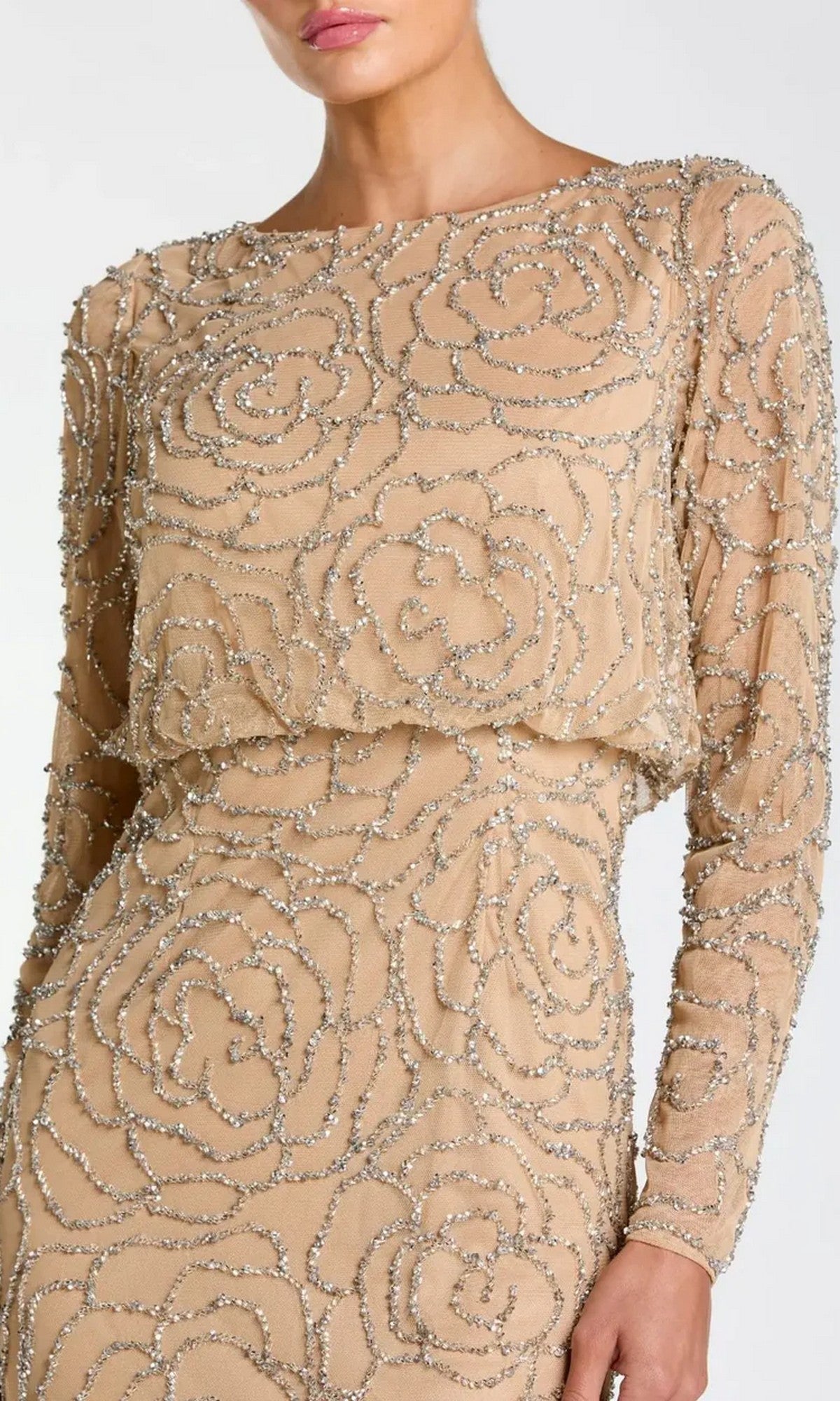 A woman is shown from mid-face to thigh wearing the Mac Duggal 6189 long formal dress in a nude shade, featuring long sleeves and intricate silver beaded floral patterns.